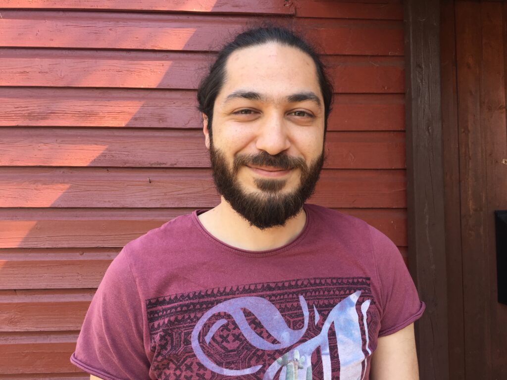 Bilal K. vor einer Holzwand. Er spricht in diesem Beitrag über Artikel 5 des Grundgesetz