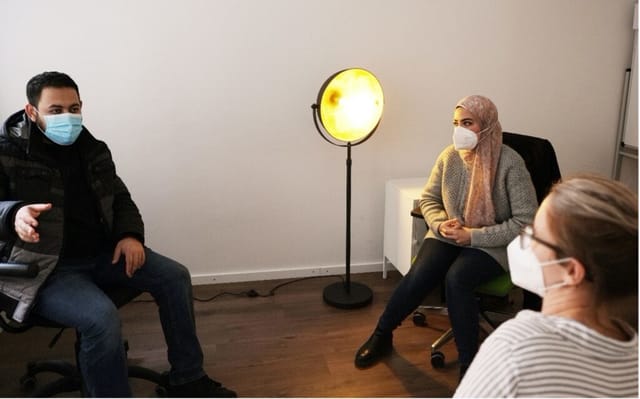 Amira Mostafa übersetzt in einem Gespräch mit einem Ehrenamtlichen für MITmacher, man sieht drei Personen mit Maske, die sich