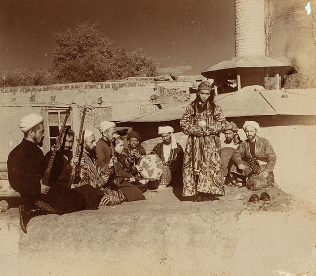 Eine Sepia-Fotografie mit erwachsenen Männern und Bacha Bazi