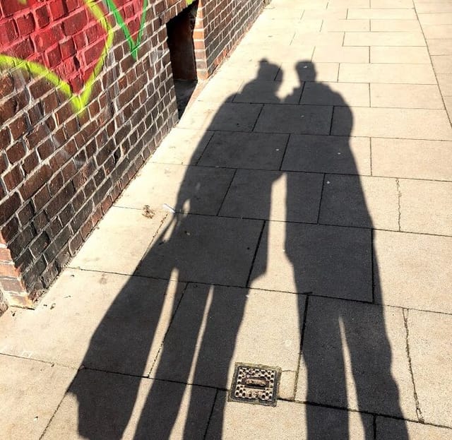 Die Schatten zweier Menschen auf einer asphaltierten Straße
