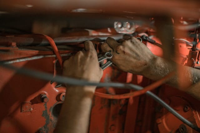 Nahaufnahme von zwei Händen, die an einem Motor arbeiten; Geschichte eines Geflüchteten