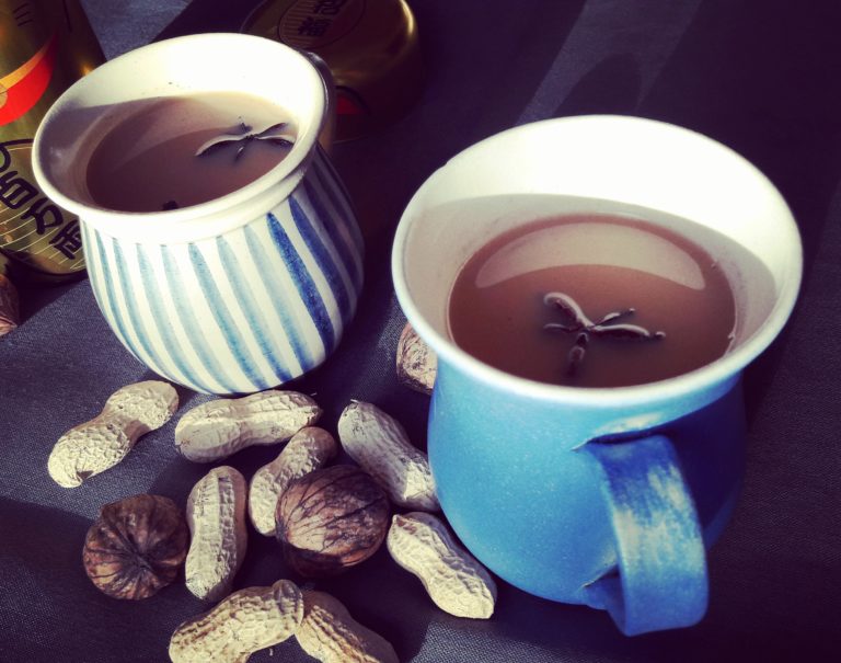 Zwei Becher Chai Latte, daneben Erdnüsse