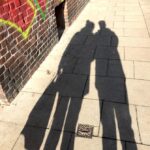 Die Schatten zweier Menschen auf einer asphaltierten Straße