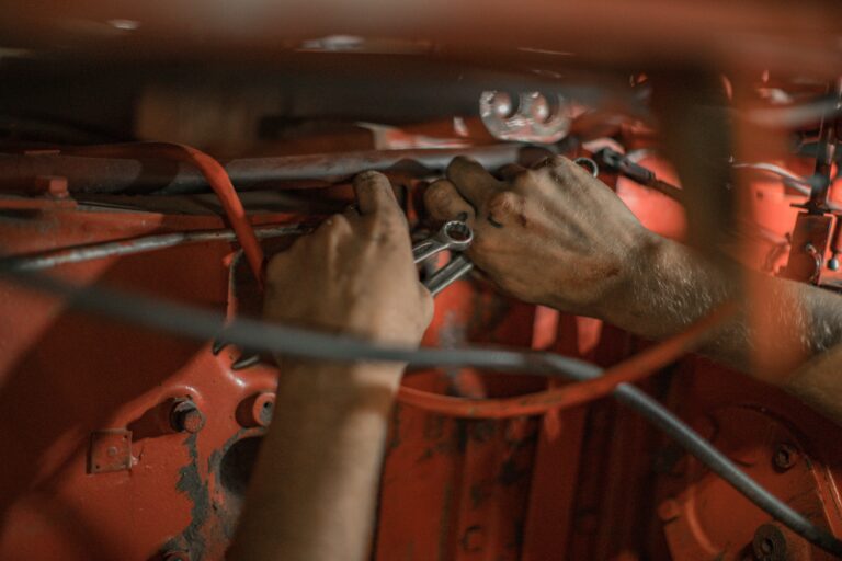 Nahaufnahme von zwei Händen, die an einem Motor arbeiten; Geschichte eines Geflüchteten