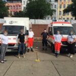 Das Women's Health Team steht vor Einsatzfahrzeugen